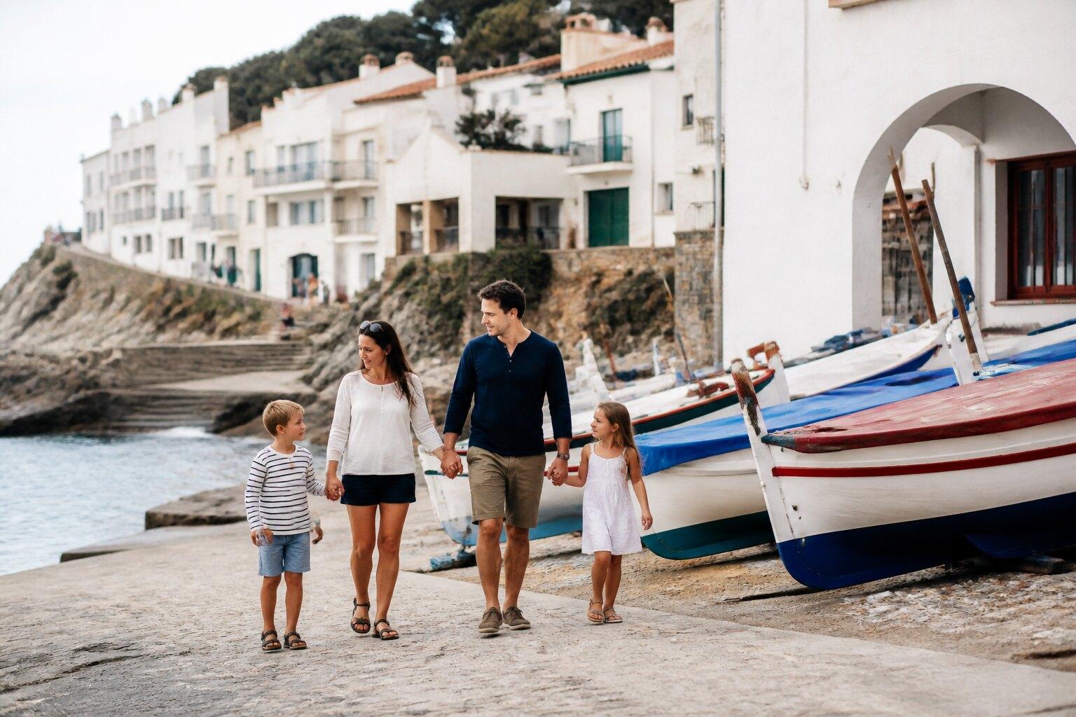 Family walking beside fishing boats on the Costa Brava