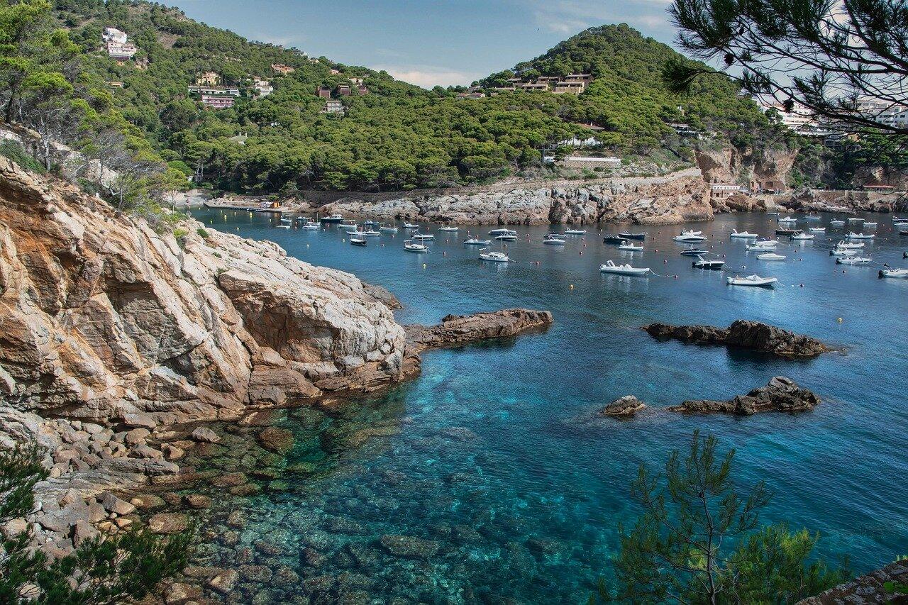 Rocky turquoise cove and anchored boats on the Costa Brava near Llafranc